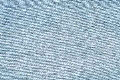 Closeup view of light blue denim fabric texture background for design Фото