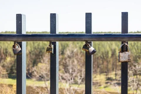 Closeup view of love padlocks hanging on a bridge fence Stock Photos