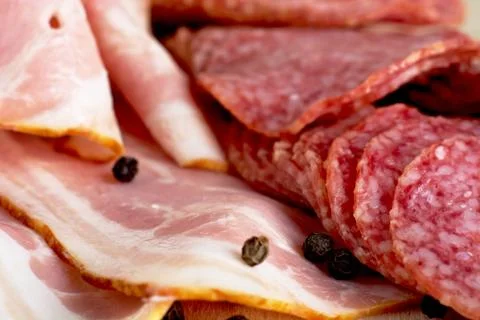 Closeup view of macro assorted slices of bacon and salami on wooden plank as Stock Photos