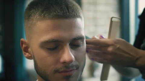 Closeup view on male's face while he's getting a haircut by barber with electric Stock Footage 93746785