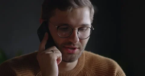 Closeup view of man in eyeglasses talking mobile phone at dark background Stock Footage 164715460