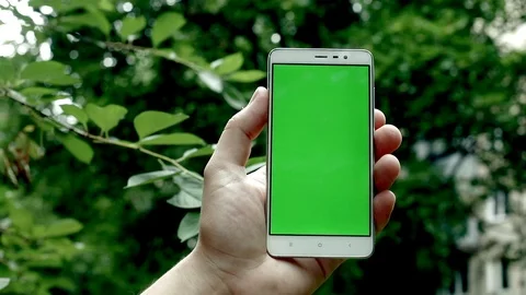 Closeup view of man hand using smartphone with empty green screen outside with 스톡 동영상 91887316