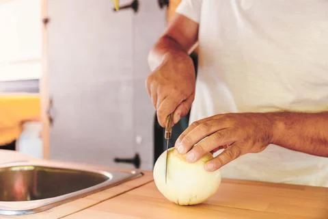 Closeup view of man hands cutting vegetables for meal in the kitchen of his.. Stock Photos