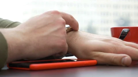 Closeup view of man having a red smartphone using a smart watch in the coff.. Stock Footage 74891179