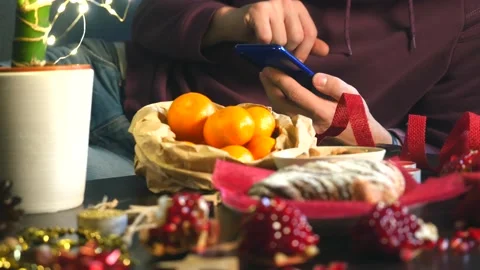Closeup view of man with mobile phone sitting near Christmas decorated table Stock Footage 144235994