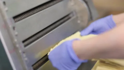 Closeup view of a man placing dough into a machine. Stock Footage 132972390