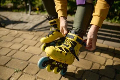 Closeup view of man putting on roller skates while sitting on bench in park Stock Photos