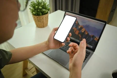 Closeup view of man sitting in front of laptop at working desk and using Stock Photos