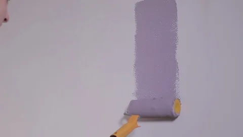 CloseUp View Of Man's Hand Painting A Wall In Violet Using A Paint Roller Stock Footage