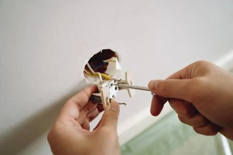 Closeup view of man's hands installing socket with screwdriver. Renovation 写真素材
