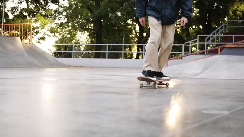 Closeup view of man's legs in black sneakers and beige pants skateboarding Видео 118809333