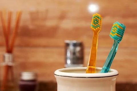 Closeup view of multicolored toothbrushes in the jar on the table in the bath Stock Photos
