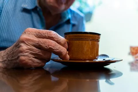 Closeup view of the old hands of an elder man taking a cup if coffee  Foto stock