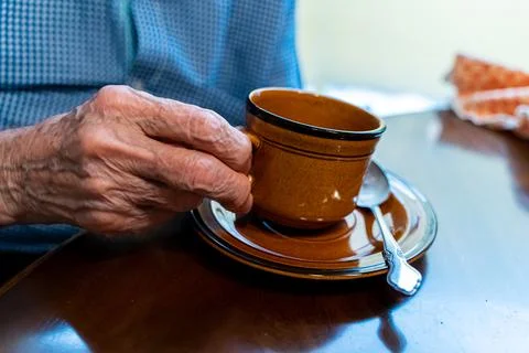 Closeup view of the old hands of an elder man taking a cup if coffee  Stock Photos