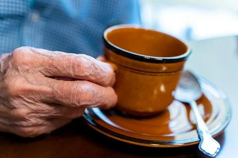 Closeup view of the old hands of an elder man taking a cup if coffee  Stock Photos