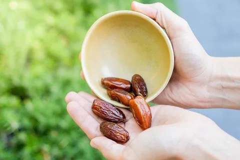 Closeup view of pile of dates rolled into a white hand. Healthy vegetable snack Stockfoto's