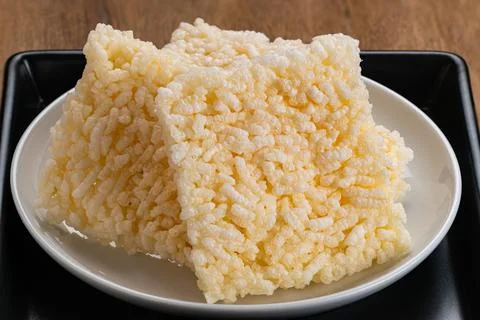Closeup view pile of square shape crispy rice crackers in white ceramic dish. Foto stock