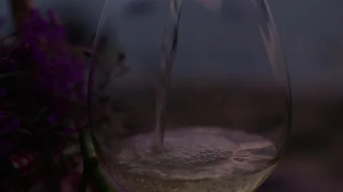 Closeup view of pouring white wine into glass on summer evening beach Stock Footage 252590481