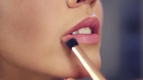 Closeup view of a professional makeup artist applying lipstick on model's lips Video stock 79677174