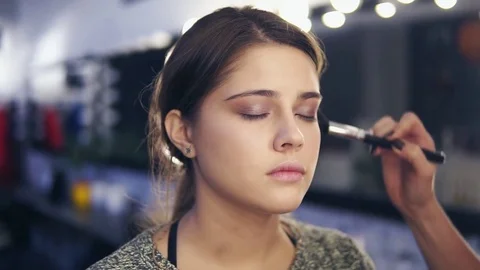 Closeup view of professional makeup artist's hands applying facial powder on Stock Footage 83165176