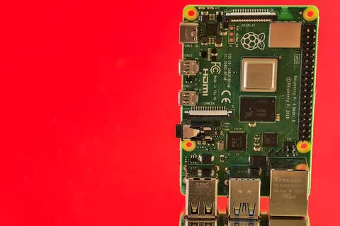 Closeup view of Raspberry Pi 4 Model B minicomputer on reflective red surface Stock Photos