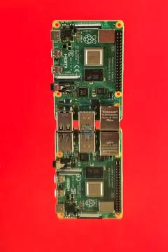 Closeup view of Raspberry Pi 4 Model B minicomputer on reflective red surface Stock Photos