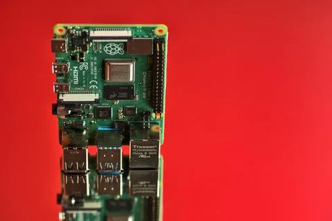 Closeup view of Raspberry Pi 4 Model B minicomputer on reflective red surface Stock Photos