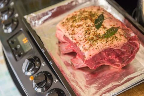 Closeup view raw beef cross rib chunk on oven tray with foil on electric cooker Stock Photos
