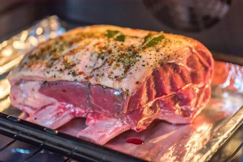 Closeup view raw beef cross rib chunk on oven tray with foil inside oven Foto stock