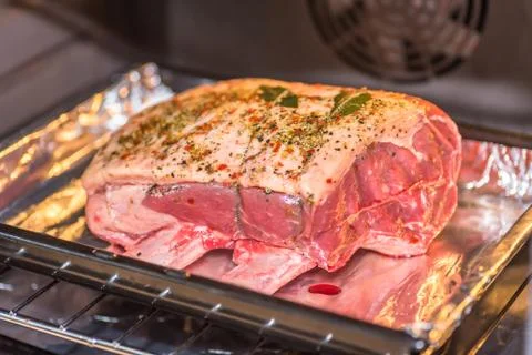 Closeup view raw beef cross rib chunk on oven tray with foil inside oven Stock-Fotos