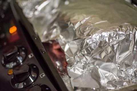 Closeup view raw beef cross rib chunk covered with cooking foil on oven tray on Stock-Fotos