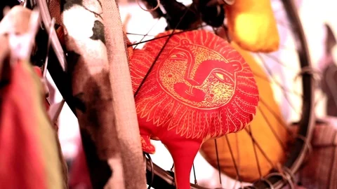 Closeup view of red handmade pillow with painted smiling lion face looking at Vídeos de archivo 116470863