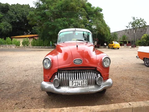 Closeup view to red retro car in the parking lot of local cuban village Stock Footage 71533172