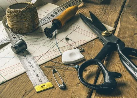 Closeup view of retro sewing tools, scissors, chalk, measuring tape lie on ta Stock Photos