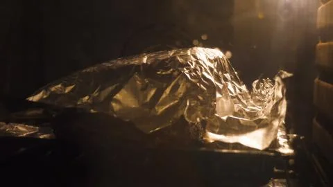 Closeup view roasting beef joint on foil covered tray cooking inside oven for Foto stock