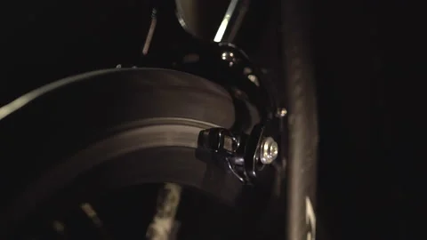 Closeup view of rotating wheel on cycling trainer in the dark, sport at home. Video stock 138155813
