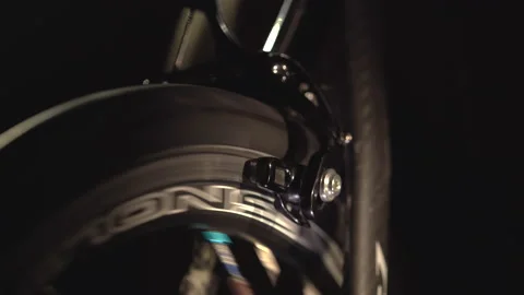 Closeup view of rotating wheel on cycling trainer in the dark, sport at home. Stockbeeldmateriaal 138155849