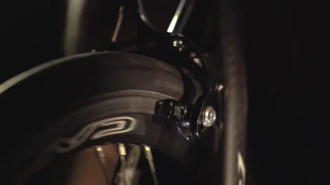 Closeup view of rotating wheel on cycling trainer in the dark, sport at home. Video stock 138156250