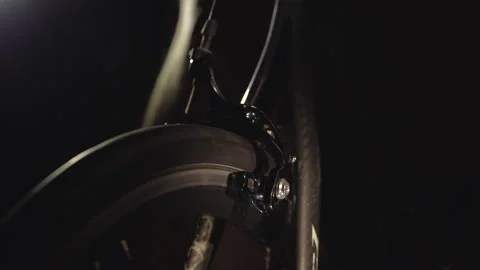 Closeup view of rotating wheel on cycling trainer in the dark, sport at home. Video stock 138156306