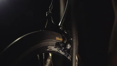Closeup view of rotating wheel on cycling trainer in the dark, sport at home. Video stock 138156445