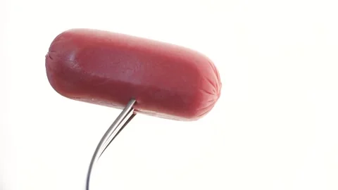 A CloseUp View of a Sausage Speared on a Fork Set Against a Bright, Colorful Stock Footage 288663990