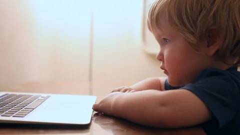 Closeup view of serious calm smart baby boy looking at laptop screen with 動画素材 105078827
