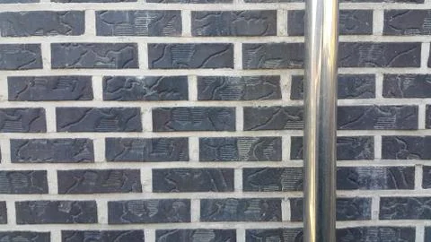 Closeup view of silver water pipe over black brick wall.in the sunshine Stock Photos