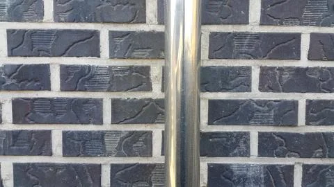 Closeup view of silver water pipe over black brick wall.in the sunshine Stock Photos