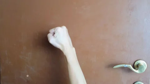 Closeup view of Someone is banging on a brown door with his right hand Stock Footage 283061539