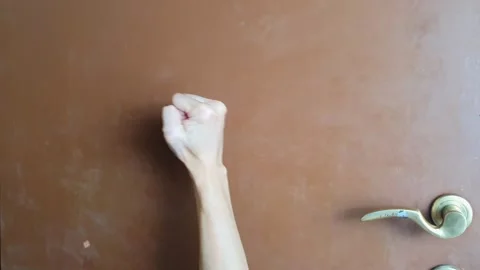 Closeup view of Someone is banging on a brown door with his right hand 스톡 동영상 283061540
