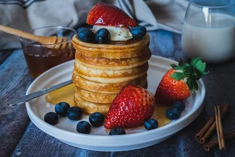 Closeup view of Stack of pancakes with honey, strawberry, blue berry and whip Stock Photos