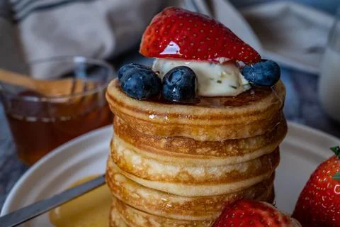 Closeup view of Stack of pancakes with honey, strawberry, blue berry and whip Stock Photos