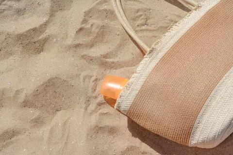 Closeup view of straw bag with sun protection product on sand, space for text Stock Photos