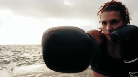 Closeup view of a strong athletic female boxer in gloves exercising with a bag Vídeos de archivo 80629048